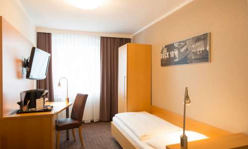 Bett und Schreibtisch im Einzelzimmer Standard im Heikotel City Nord Bett und Schreibtisch im Einzelzimmer Standard im Heikotel City Nord