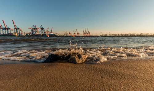 Blick vom Strand auf Hafenkräne der Stadt